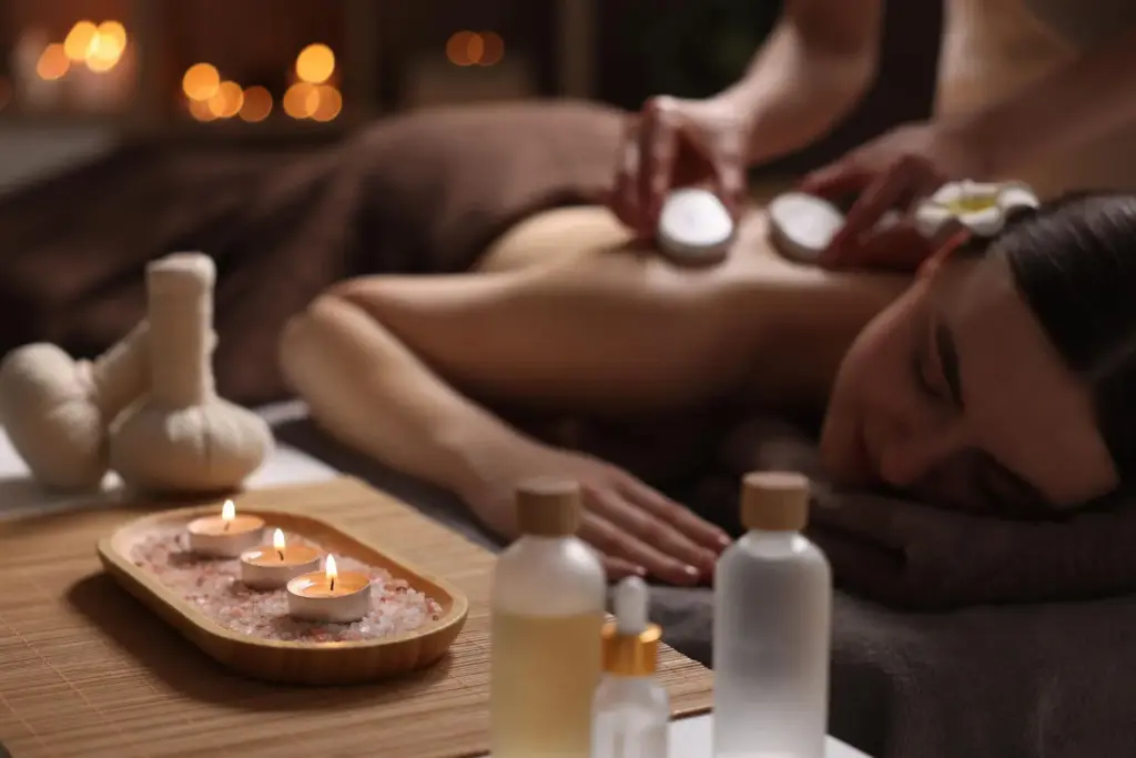 Frau bei Massage mit Öl und Kerzen